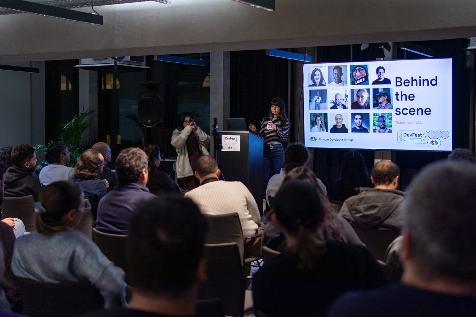 Organizer presenting the 'Behind the scene' slide at DevFest Berlin 2025