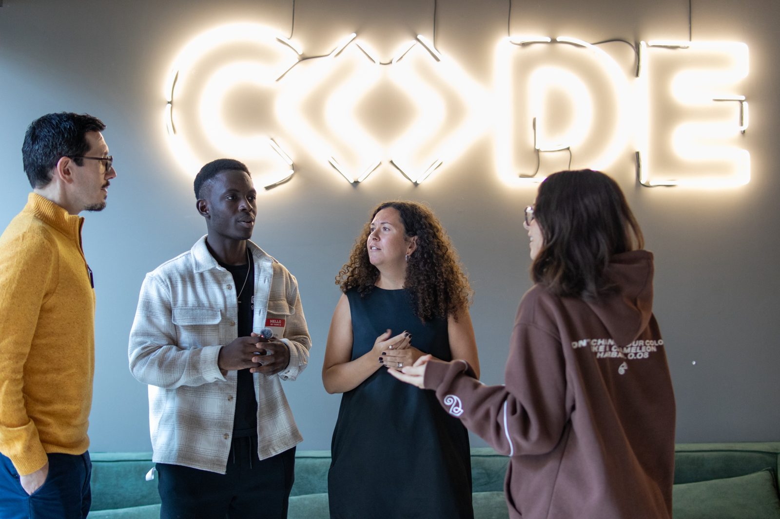 Attendees chatting under the CODE neon sign
